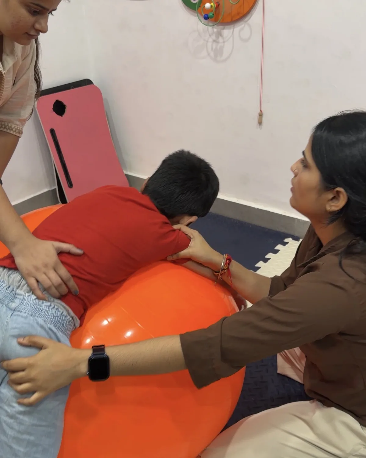 Therapists supporting a boy on a therapy ball
